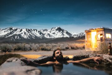 man relaxing in a spring next to his rv