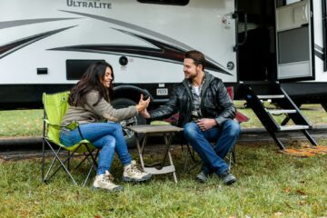 man and woman sitting on chair in front of RV